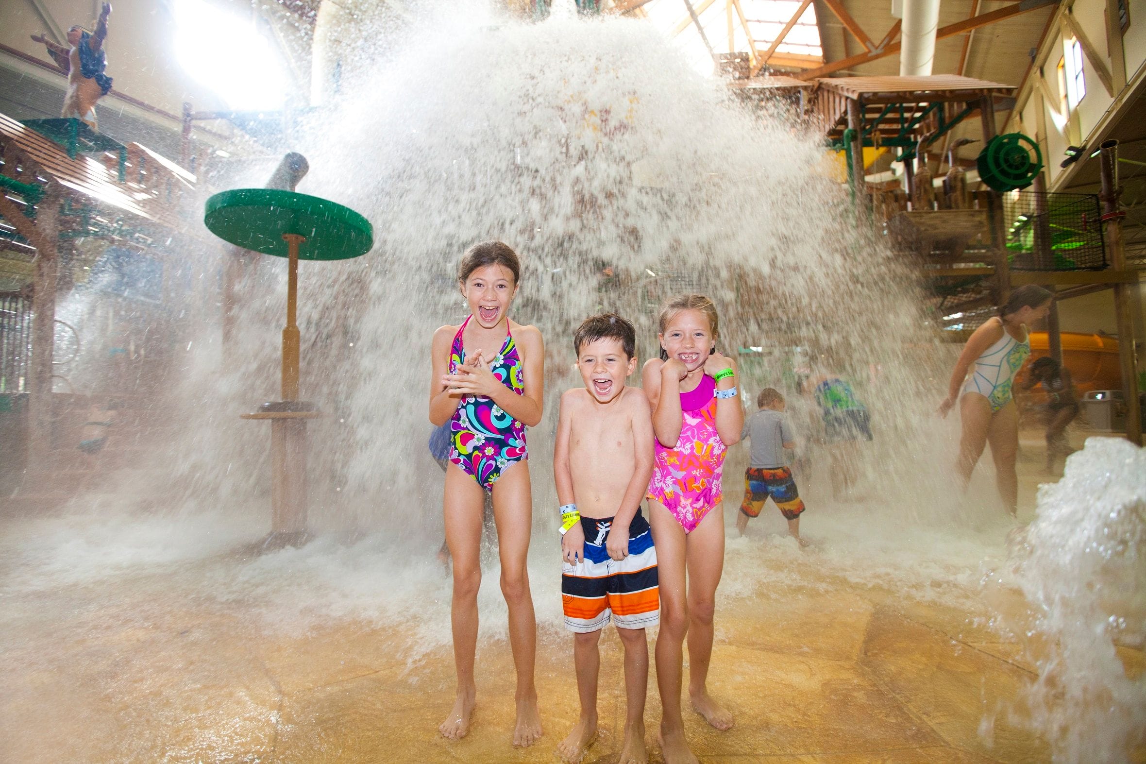 Kids smiling as a giant bucket of water sprays down on them at Great Wolf Lodge indoor water park