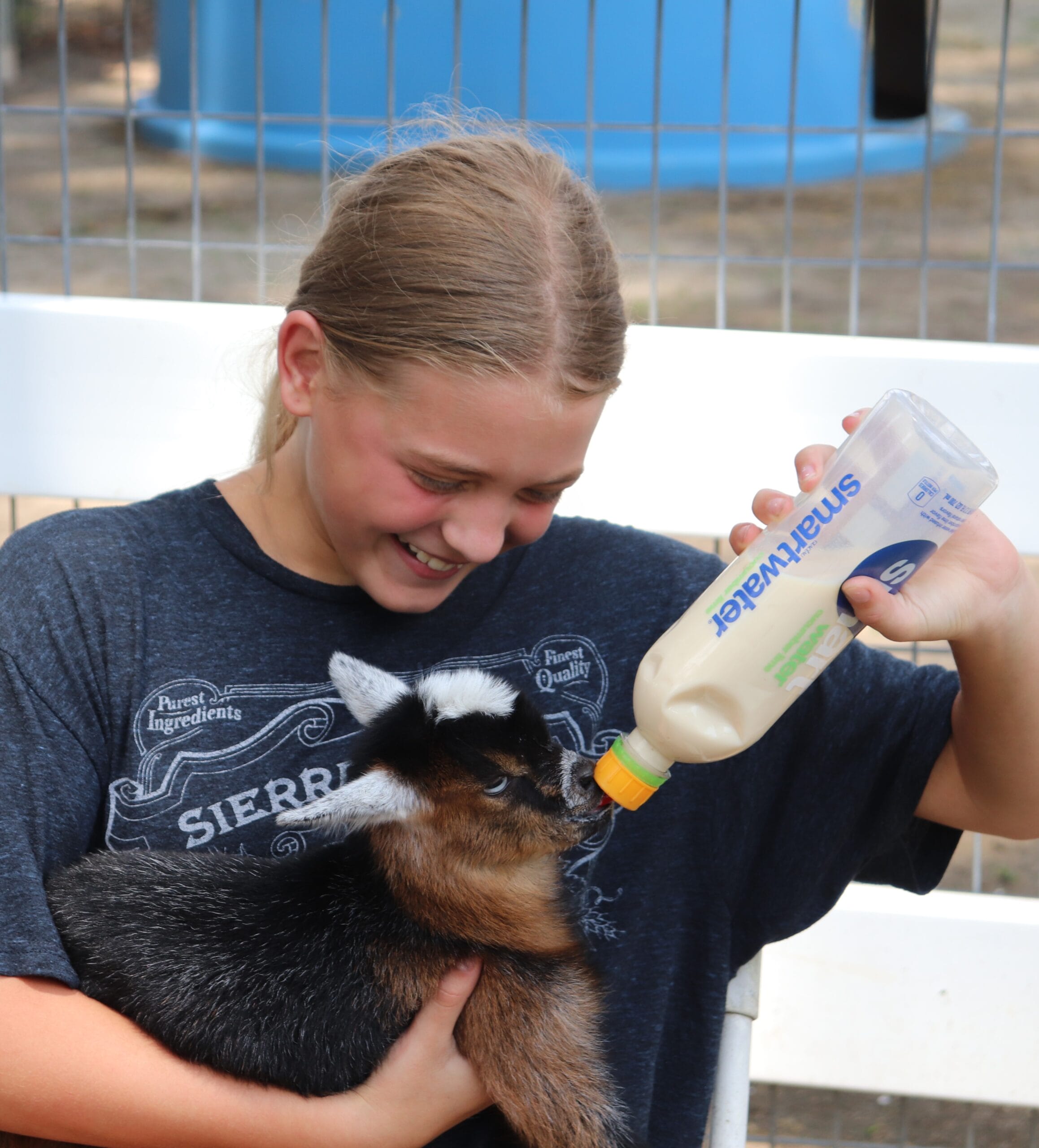 Camper bottle feeding a baby goat at Hunt Club Farm.