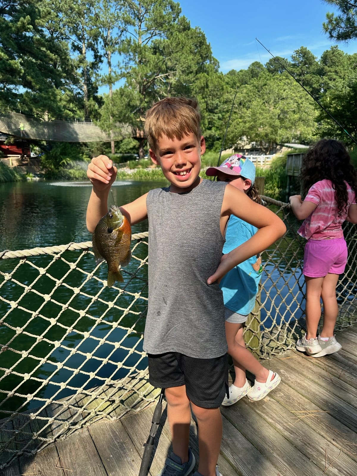 Child holding up a fish he caught at Summer Camp at Hunt Club Farm