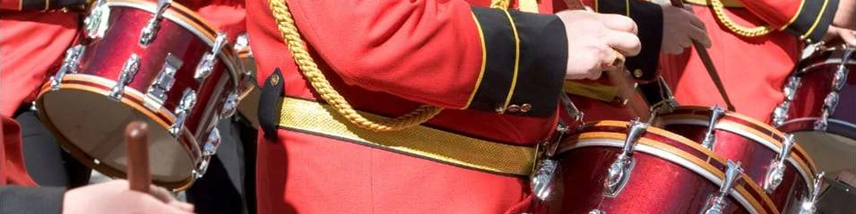 Marching band drummers in red uniforms during a holiday parade